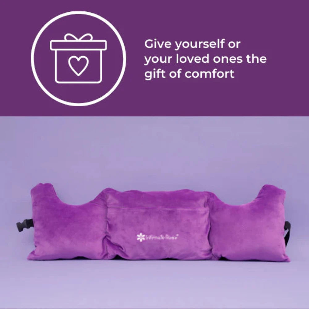 Against a purple background, the Post-Surgery Mastectomy Pillow from Intimate Rose is shown with armrests. In the top left corner, a white gift icon with a heart is accompanied by the text: "Give yourself or your loved ones the gift of comfort.