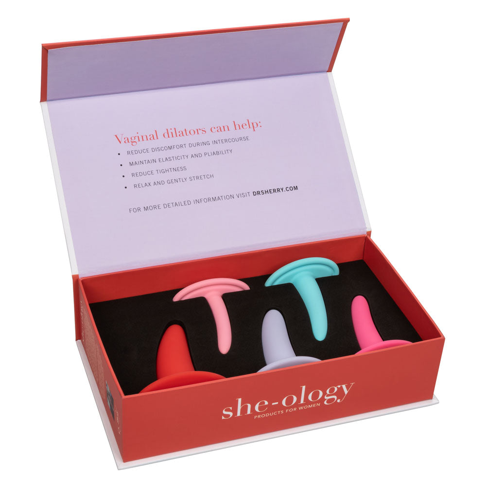 An open box from Calexotics' She-ology™ 5-piece Wearable Vaginal Dilator Set contains wearable vaginal dilators in various sizes and colors (pink, light pink, blue, and purple). The box's lid lists benefits such as reducing discomfort, maintaining elasticity, and promoting pelvic floor health by relaxing and gently stretching the vaginal muscles.