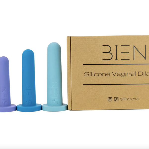 A set of four Bien Silicone Vaginal Dilators from BIEN Australia features medical-grade silicone in graduated sizes, arranged next to a cardboard box labeled "Bien Silicone Vaginal Dilators - Medium Set." The dilators are displayed in shades of pink, purple, blue, and aqua, from smallest to largest.