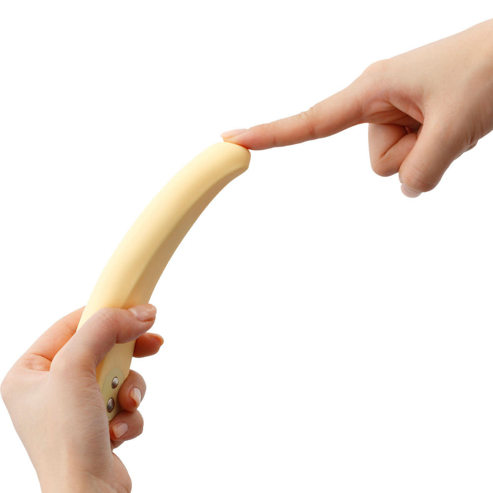 A hand holds the Iroha Mikazuki – Gentle Slim Vibrator for Beginners by Iroha as another presses its tip, showing the flexibility of its body-safe silicone against a white background.