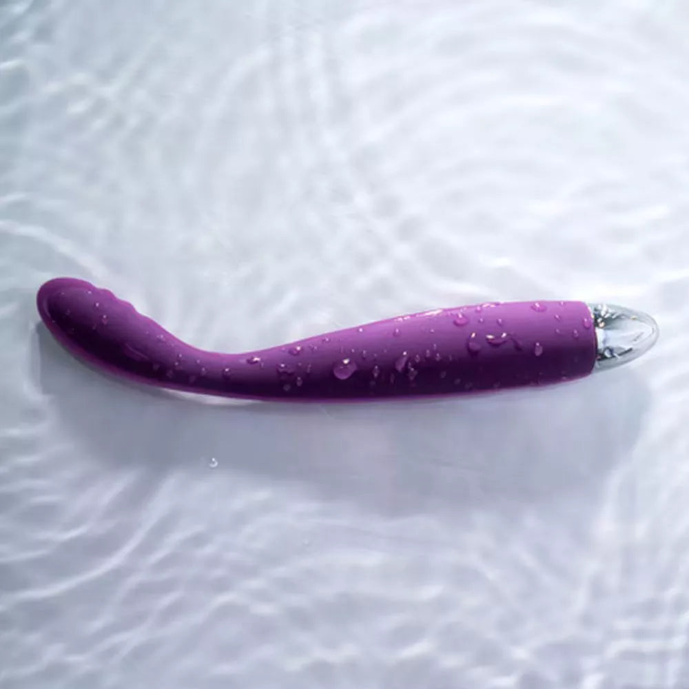 The Svakom Cici – a slim, flexible G-spot vibrator from Svakom with a metallic end and body-safe silicone—rests on a wet surface, surrounded by water droplets and ripples.