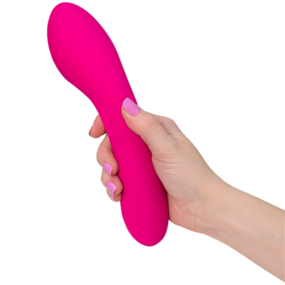 A hand with pink-painted nails holds The Swan Wand, a pink curved vibrator by the brand Swan, featuring a smooth texture. The device has a bulbous end and tapers slightly towards the middle. The background is plain white.