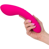 Close-up of a hand holding the bright pink, curved Swan Wand by Swan, featuring Dual PowerBullet motors. The person's nails are painted to match the color of The Swan Wand. The background is white.