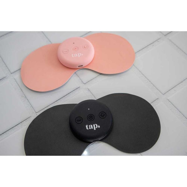 Close-up of two Tap. 2 Wearable TENS Machines by Tap Health on a tiled surface: one pink and one black, each featuring a round control pad labeled "tap." Both devices provide portable pain relief with two buttons, designed with soft, flexible edges.