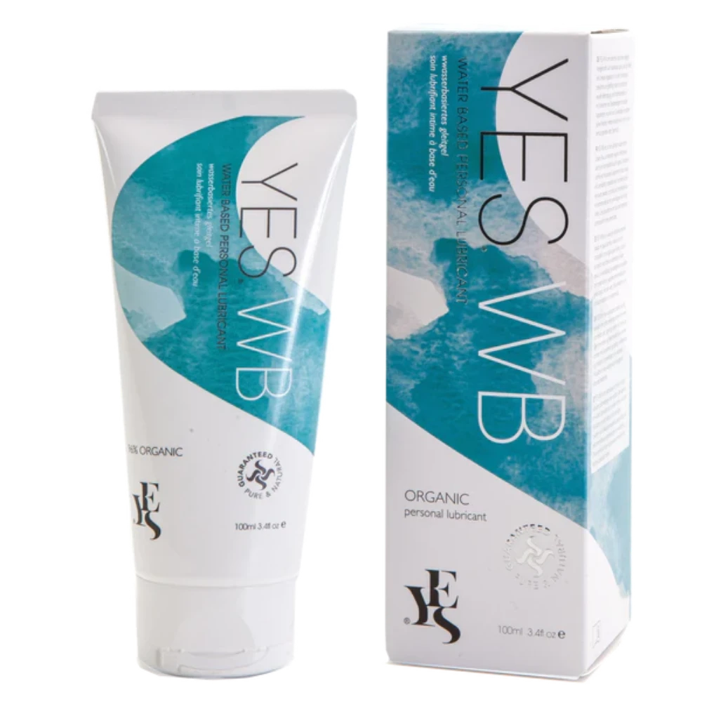 A 100ml tube of YES® WB Water-Based Lubricant by YES® is positioned beside its box packaging. The tube and box feature a white and teal design with product information and logos indicating it is pH balanced, certified organic, and provides long-lasting hydration.